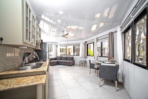 Eine moderne Küche mit Spüle, ein Essbereich mit Stuhl und Tisch sowie ein Wohnbereich mit Sofa.