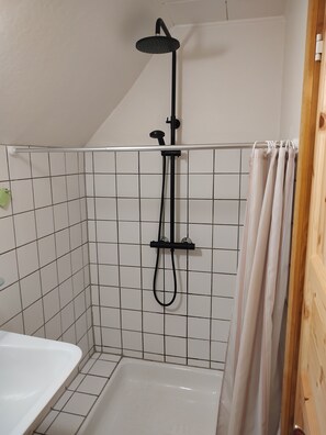 Une douche équipée d’un pommeau de douche à main, d’un pommeau de douche vertical en forme de pluie et d’un accessoire de douche à main.