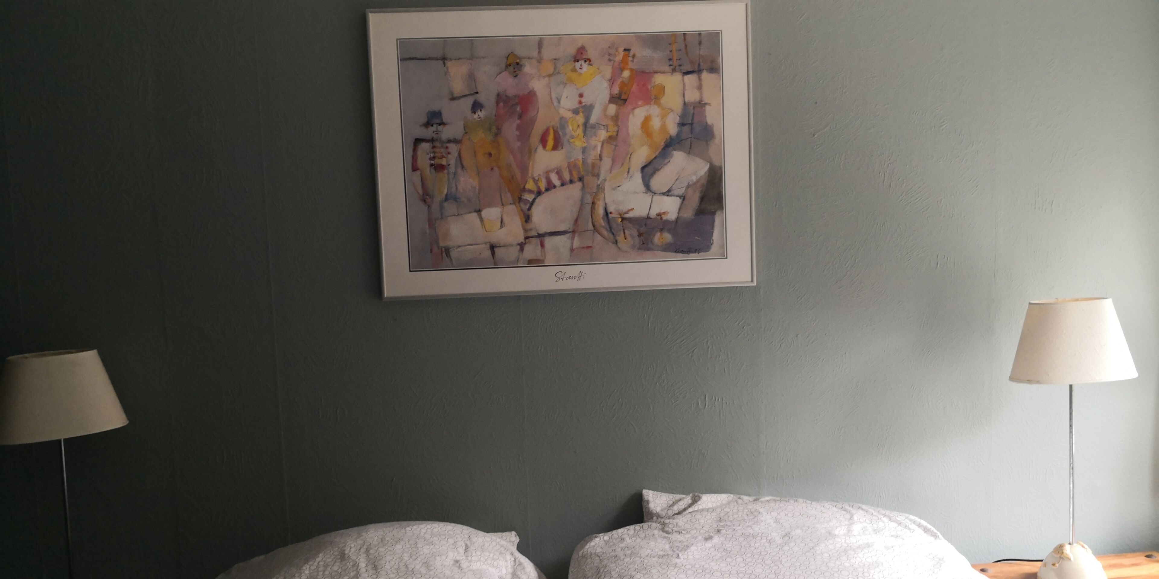 A room with a bed, two bedside lamps, and a framed abstract painting on the wall.