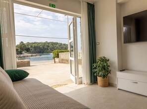 Une chambre avec un lit, une télévision, une plante et une vue sur une étendue d’eau et de la verdure.