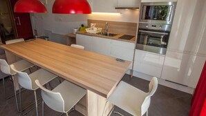 Eine moderne Küche mit einer Holztresle, weißen Schränken, Edelstahlgeräten und roten Pendelleuchten.