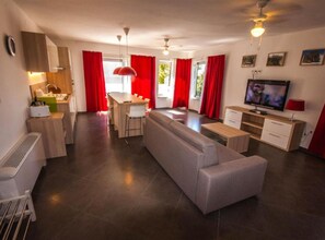 Ein modernes Wohnzimmer mit Sofa, Esstisch und Küchenbereich.