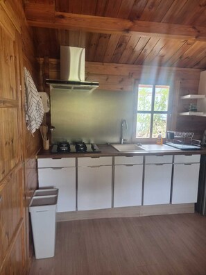 A compact kitchen with wooden walls, a window, and a sink.