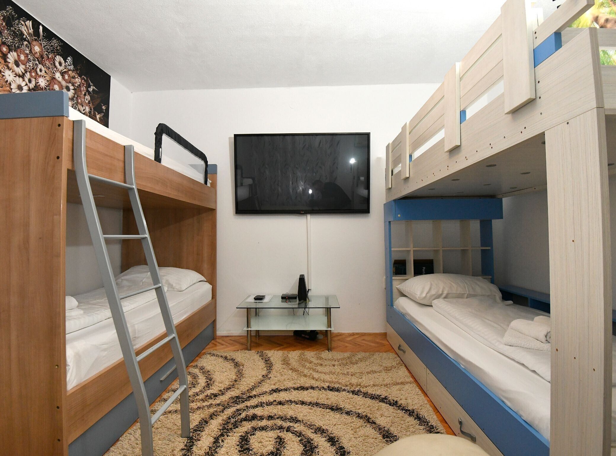 A room with bunk beds, a TV, a small table, and a patterned rug.
