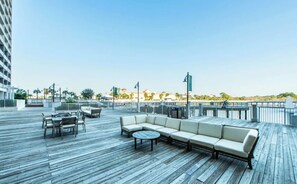 En tagterrasse med udendørs siddepladser og udsigt over stranden, under en klar himmel.