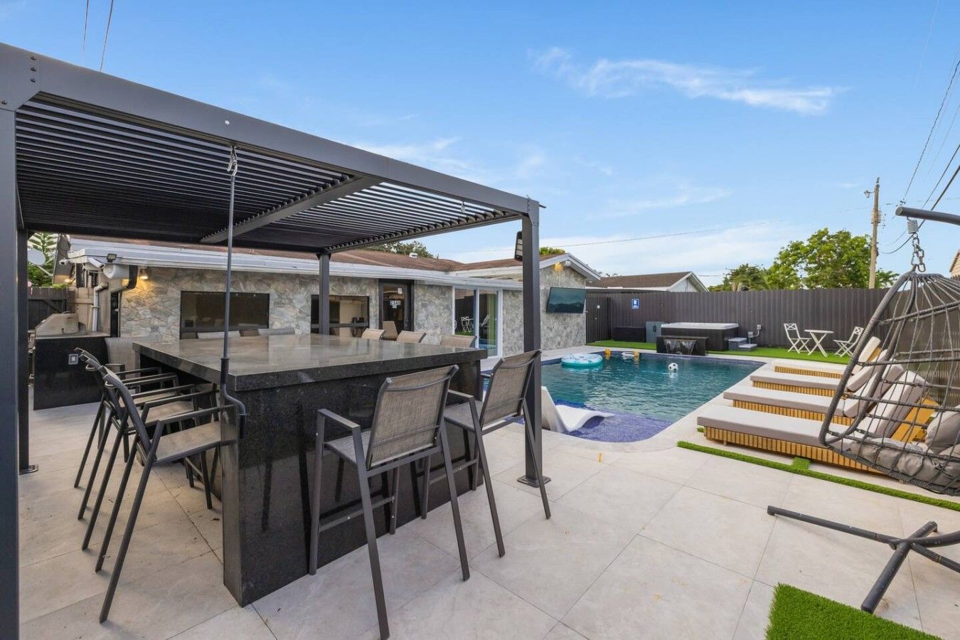 Ein Außenbereich mit Bar, Pool und Liegestühlen.