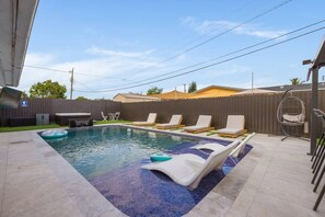 A rectangular swimming pool with a tiled edge, surrounded by lounge chairs and a hot tub. - Pool + Hot Tub | Outdoor Kitchen | Hollywood FL (Hollywood)