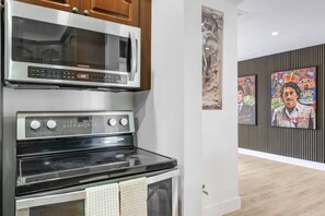 A kitchen with a microwave, oven, and a wall-mounted artwork. - Pool + Hot Tub | Outdoor Kitchen | Hollywood FL (Hollywood)