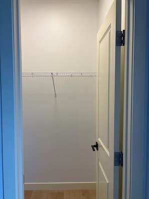 Ett rum med en vit dörr, ett metallställ på väggen och ett trägolv.