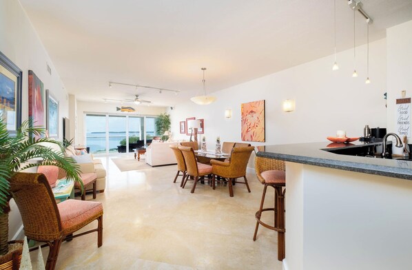 A modern kitchen with a dining area, large windows, and a view of the outdoors. - Mariners Club Penthouse Unit 335, VRNR Luxury Collection- VRBO Preferred Partner (Key Largo)