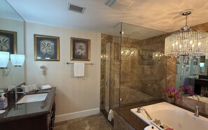 Ein modernes Badezimmer mit einer gläsernen Duschkabine, einer großen Badewanne und einer Kristallleuchter.