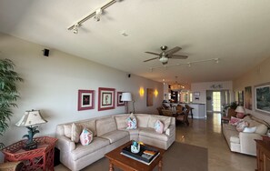 Ein Wohnzimmer mit einem beigefarbenen Sofa, einem Couchtisch und einem Deckenventilator.