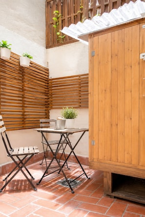 A patio with a wooden table and chairs, a small cabinet, and potted plants. - Gotico beach (Barcelona)