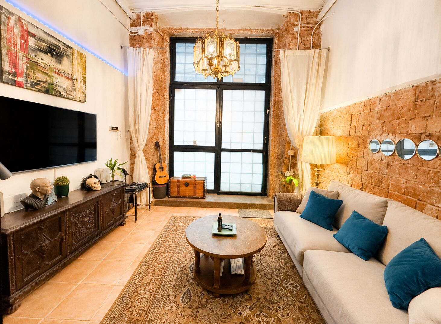 A living room with a sofa, coffee table, TV, guitar, and decorative items.