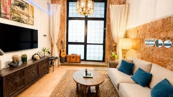 A living room with a sofa, coffee table, TV, guitar, and decorative items.