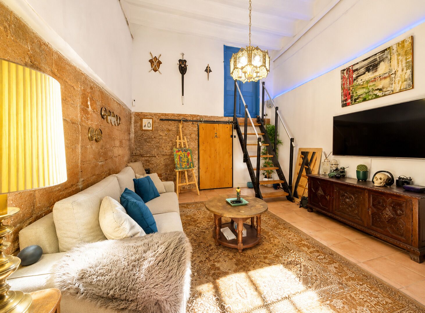 A living room with a sofa, a coffee table, a TV, and a staircase.