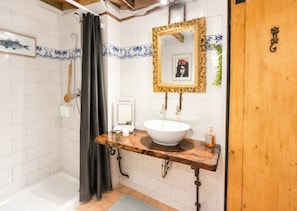 A bathroom with a white sink, a wooden vanity, a shower with a black curtain, and a decorative mirror. - Gotico beach (Barcelona)