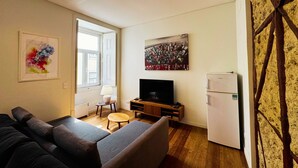 A living room with a sofa, a television, a small table, and a refrigerator. - Lux Old Town (Lisboa)