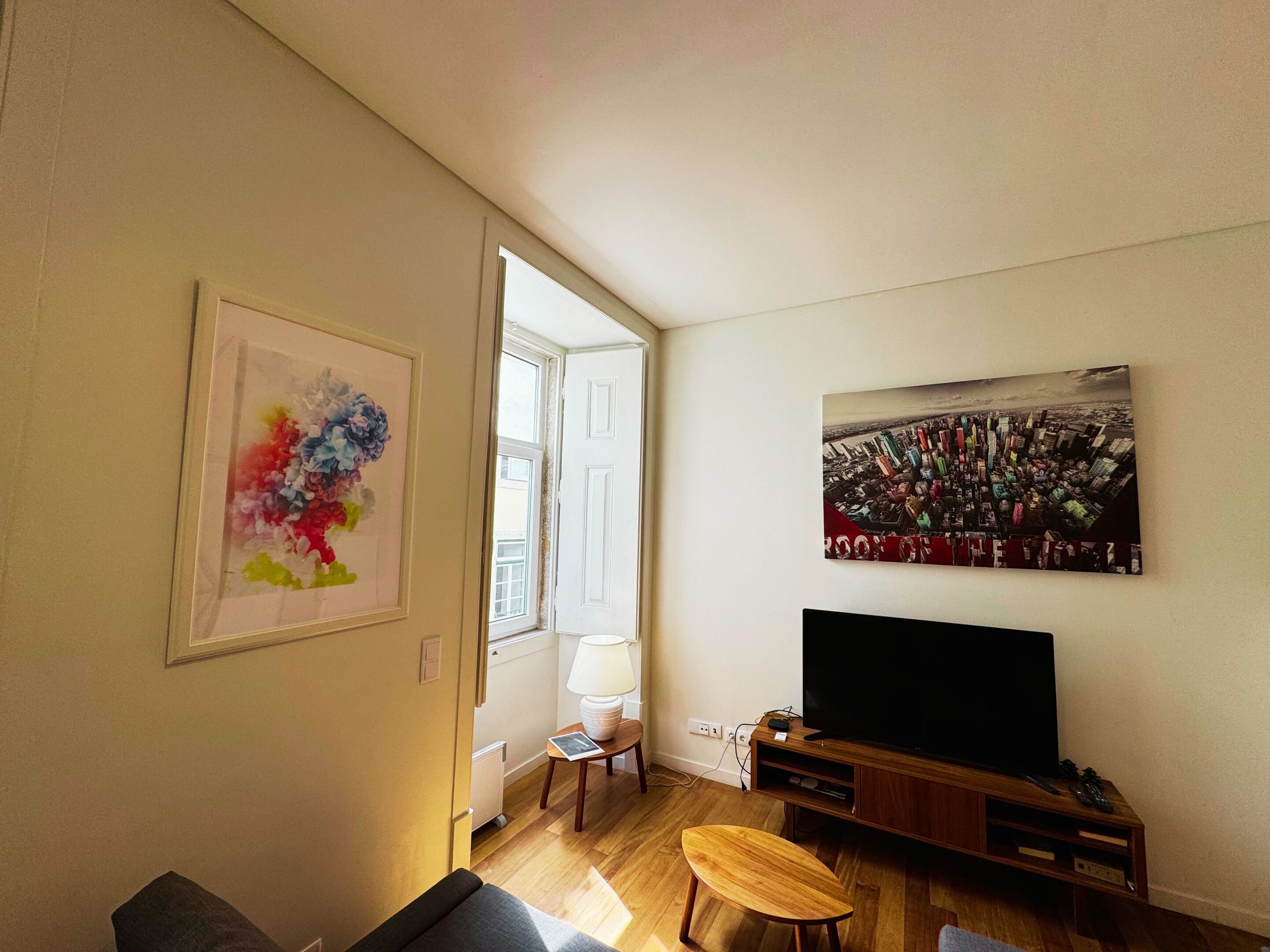 Ein Wohnzimmer mit Fernseher, Holzboden und einer Tür, die nach draußen führt.