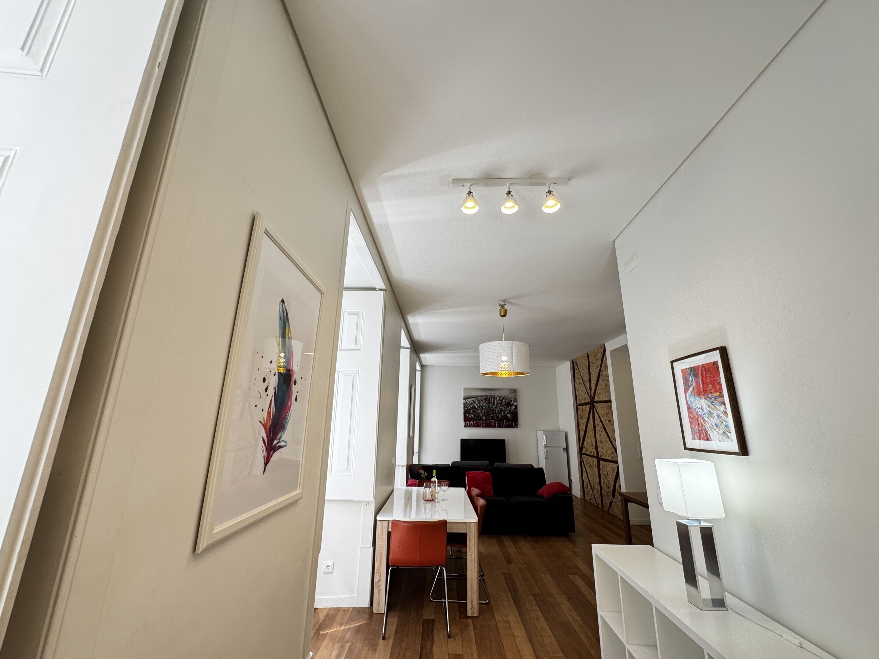 A modern interior with a dining area, a living room, and a hallway.