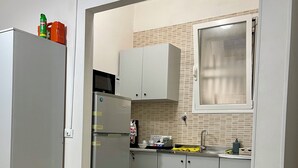 Une cuisine équipée d’un réfrigérateur, d’un four à micro-ondes, de placards et d’une fenêtre.