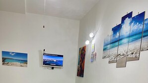 Un espace repas comprenant une table, des chaises, un canapé vert, un téléviseur et des œuvres d’art murales.
