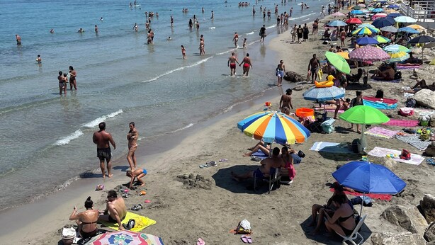 Une plage où l’on peut se baigner et bronzer, avec des parasols et des chaises de plage.