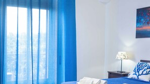 Une chambre à coucher avec un lit, un banc en bois, une table de chevet, une lampe et un tableau accroché au mur.
