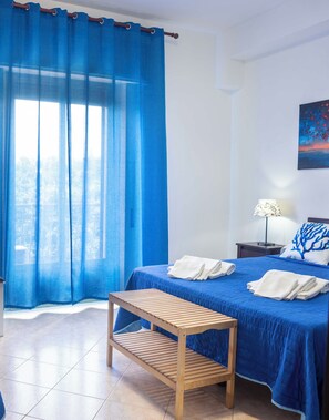 Ein Schlafzimmer mit einem Bett, einer hölzernen Bank, einem Nachttisch, einer Lampe und einem Bild an der Wand.