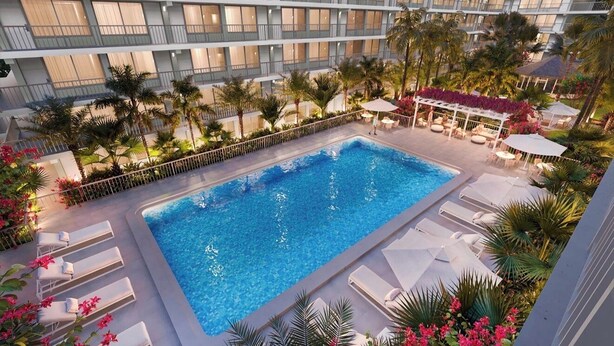 Ein Hotelpoolbereich mit rechteckigem Pool, Liegestühlen und Palmen.