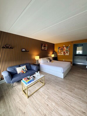 Ett modernt hotellrum med en soffa, en säng, ett soffbord och ett trägolv.