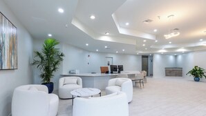 Eine moderne Lobby mit weißen Möbeln, einem Empfangstresen und einer großen Pflanze in einem Topf.