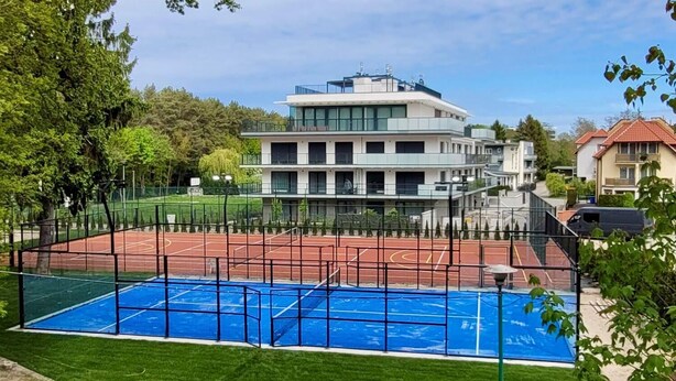 Ein mehrstöckiges Gebäude mit Tennisplatz und Schwimmbad.