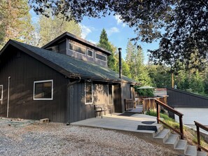 Un bâtiment à deux étages, à l’extérieur sombre, doté d’un patio couvert et d’un escalier menant à une terrasse.