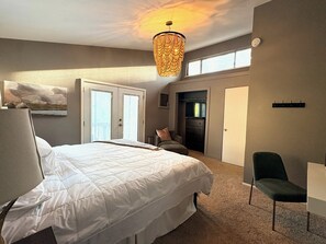 Une chambre à coucher avec un grand lit, une chaise, un bureau, un lustre et un placard.