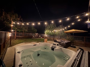 A hot tub with a wooden deck and string lights. - Modern Mountain Getaway 12 Miles to Yosemite, Private Yard, Fire Table (Oakhurst)