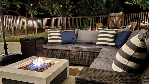 A patio with a fire pit, wicker furniture, and a wooden fence. - Modern Mountain Getaway 12 Miles to Yosemite, Private Yard, Fire Table (Oakhurst)