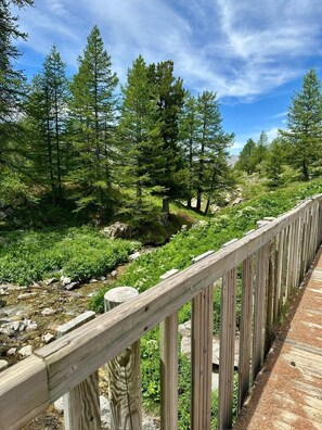 A wooden deck overlooking a forested area with a stream. - Luxury apartment, South-facing terrace, Exceptional view, Lock-up garage (Isola)