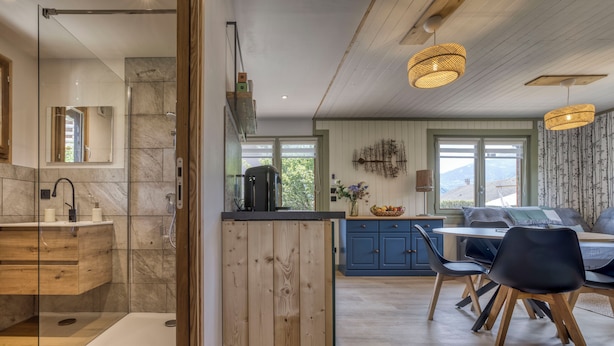 A modern kitchen with a wooden island, a dining area with blue cabinets, and a view of the outdoors. - Mazot des Outards - Swimming pool - Air conditioning - Cozy garden (Passy)