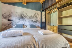 A bedroom with a mountain mural, a bed with two pillows, a wooden dresser, and a wardrobe. - Mazot des Outards - Swimming pool - Air conditioning - Cozy garden (Passy)