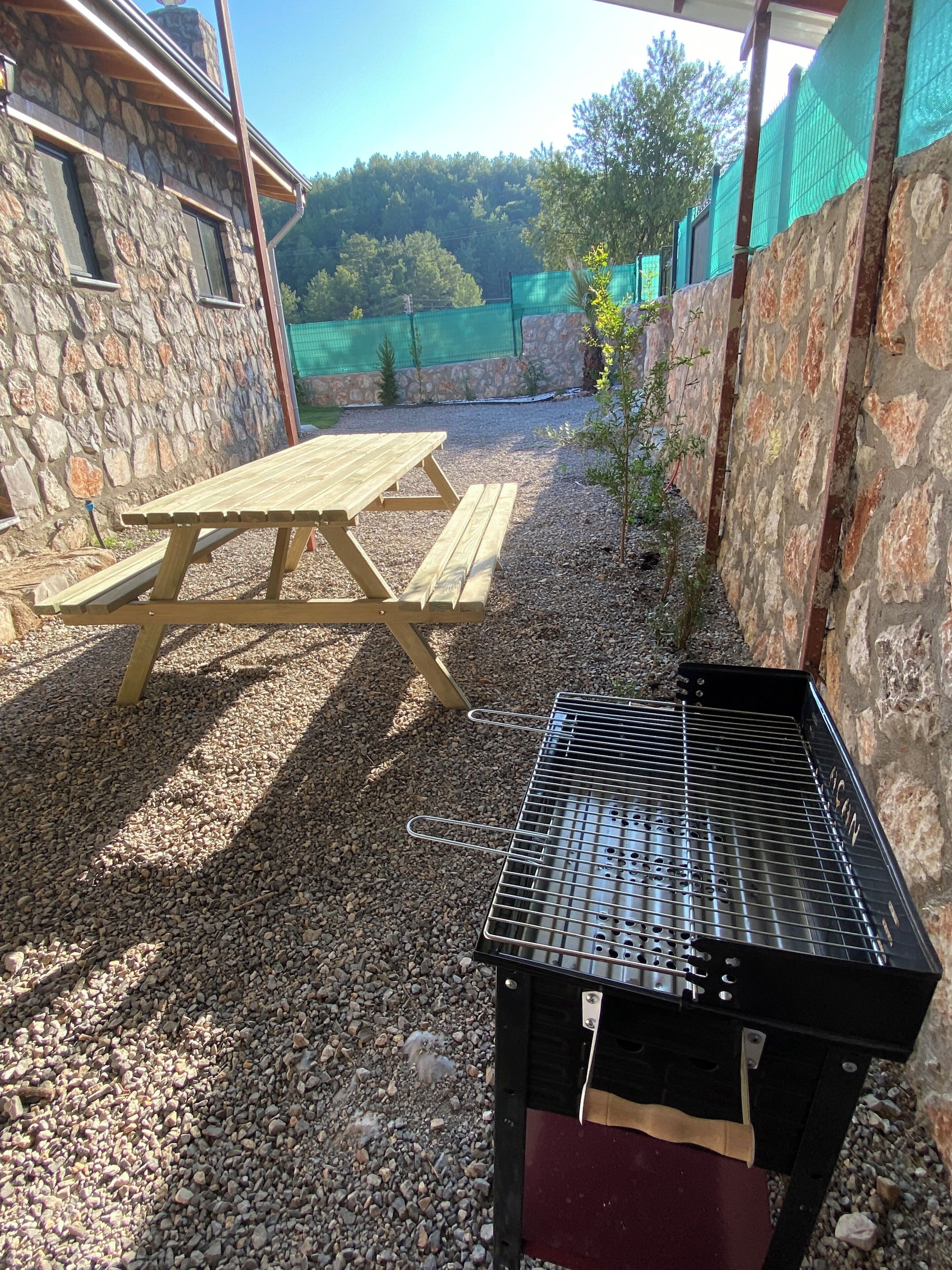 A patio area with a wooden picnic table and a barbecue grill.