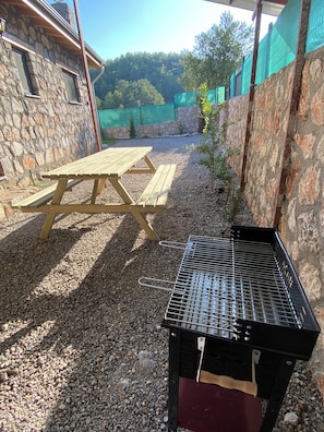 Eine Terrassenfläche mit einem Holztisch und einem Grill.