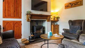 Een gezellige woonkamer met een open haard, houten meubels en een flatscreen televisie.