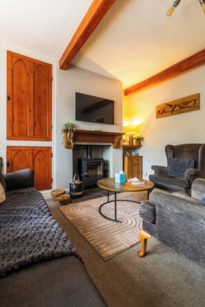 Uma sala de estar acolhedora com lareira, mobiliário de madeira e televisão de tela plana.