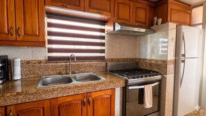 Eine Küche mit Holzausstattung, einer Edelstahlspüle, einem Gasherd und einem Kühlschrank.
