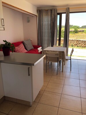 A compact living space with a kitchenette, a dining area, and a view of the outdoors.
