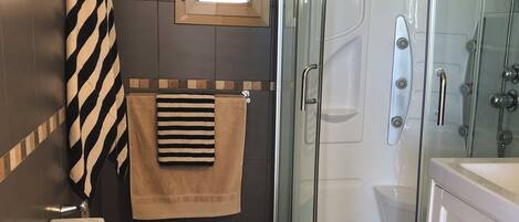 Casa de banho moderna com sanita, bidé e cabine de duche com parede de vidro.