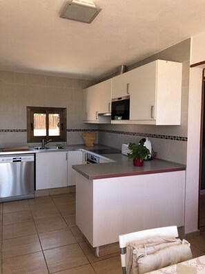 A modern kitchen with a dishwasher, oven, microwave, and a small island with a plant.