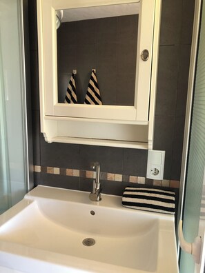 A bathroom with a white sink, a mirror above it, and a tiled backsplash.