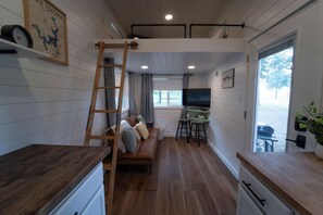 A compact room with a wooden ladder, a sofa, a TV, and a desk. - Less House, More Lake | Perfect for Couples (Kingston)